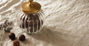 Glas-bonbonniere med chokoladekonfekt og messing-låg på linnedduk