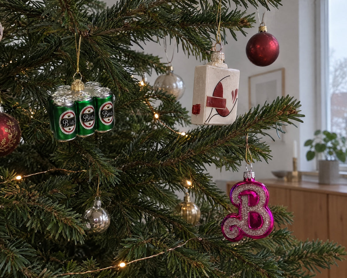 Fun glass Christmas baubles shaped like a six-pack, a boxed wine and a pink B on a Christmas tree