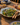 Stor salatskål i håndmalet keramik med grøn salat på et spisebord